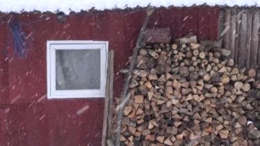 Yakacak odun yığını ahır duvar ve kış kar yağışı yakınındaki