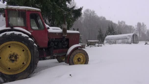 Snowfall  on old retro tractor and plastic greenhouse — Stock Video