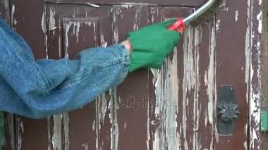 Metal fırça ile ahşap kapı üzerinden eski kahverengi boya kazıma