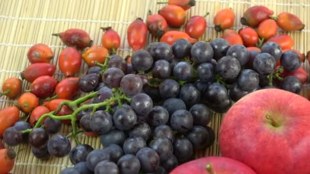 健康食品果物背景を回転させます 北のブドウ 野生ローズヒップ 赤いリンゴ — ストック動画