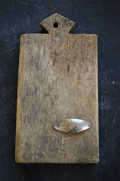 Still life with old  kitchen cutting board and metal spoon-bait fish — Stock Photo, Image