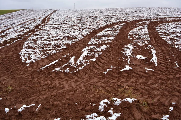 Campo arado de otoño con trazas de tractores y primera nieve — Foto de Stock