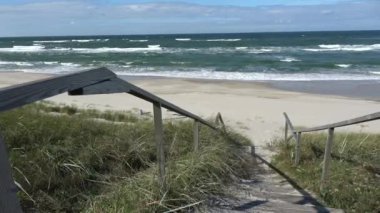 Kumsaldaki ahşap merdivenler ve Baltık deniz dalgaları