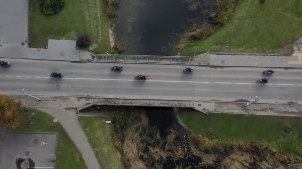 都市の川の橋の上にオートバイのバイカーの列 シーズンの終わり 空中ビュー — ストック動画