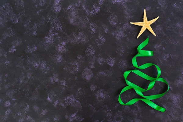 Kerstboom gemaakt van lint en zeester op donkere achtergrond. Bovenaanzicht — Stockfoto