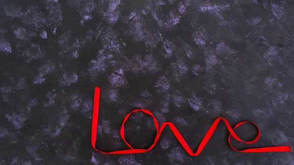 Word love made of red ribbon on dark background — Stock Photo, Image