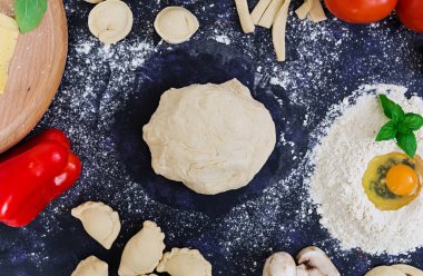 Ham pizza hamur malzemeleri ve baharat koyu arka plan üzerinde. Üstten Görünüm