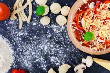 Ham pizza hamur malzemeleri ve baharat koyu arka plan üzerinde. Üstten Görünüm