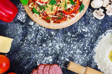 Ham pizza hamur malzemeleri ve baharat koyu arka plan üzerinde. Üstten Görünüm