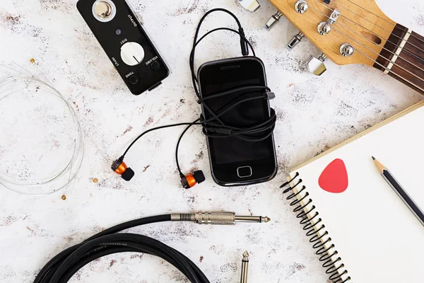 Music stuff. Guitar, guitar pedal, headphone, mobile phone on white background. Top view. Flat lay