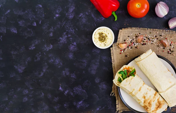 Koyu arka plan üzerinde malzemelerle shawarma sandviç. Üstten Görünüm