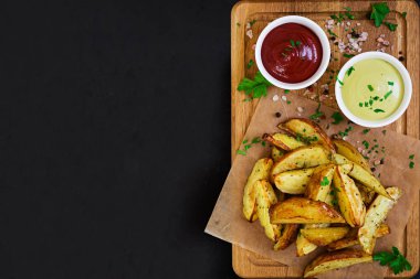 Fırında patates sosu ve baharatlar koyu arka plan üzerinde