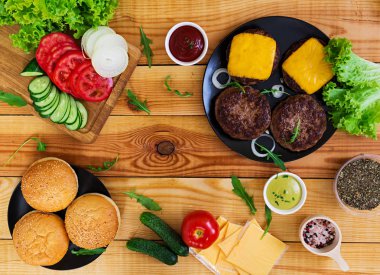 Ahşap arka plan burger için malzemeler. Üstten Görünüm