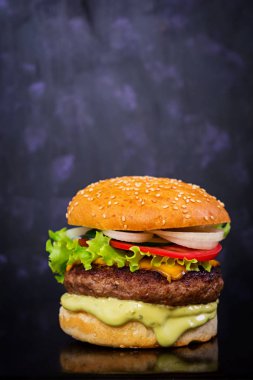 Koyu arka plan üzerinde lezzetli el yapımı burger. Görünümü Kapat