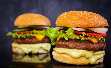 Koyu arka plan üzerinde lezzetli el yapımı burger. Görünümü Kapat
