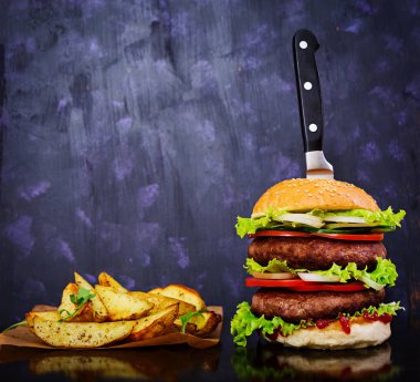 Koyu arka plan üzerinde lezzetli el yapımı burger. Görünümü Kapat