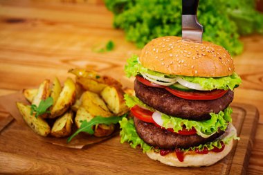Ahşap arka plan üzerinde lezzetli el yapımı burger. Görünümü Kapat