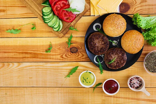Ahşap arka plan burger için malzemeler. Üstten Görünüm