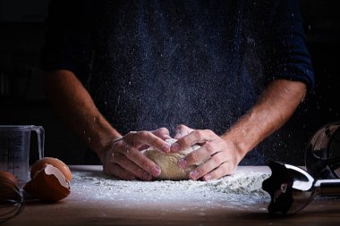 Male hands making dough for pizza, dumplings or bread. Baking concept. clipart