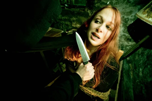 Giovane donna legato alla sedia con Mans mano che tiene coltello — Foto Stock