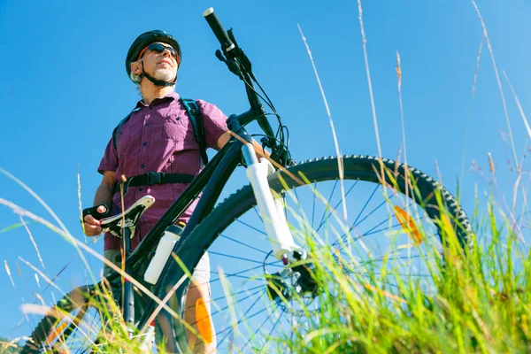 Sênior com bicicleta de montanha em pé no topo de uma colina — Fotografia de Stock