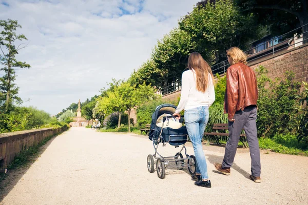 Young Parents With Baby Stroller In The Park — Stock Photo, Image