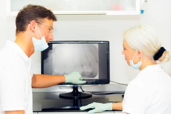 Dentista y su asistente mirando rayos X dentales — Foto de Stock
