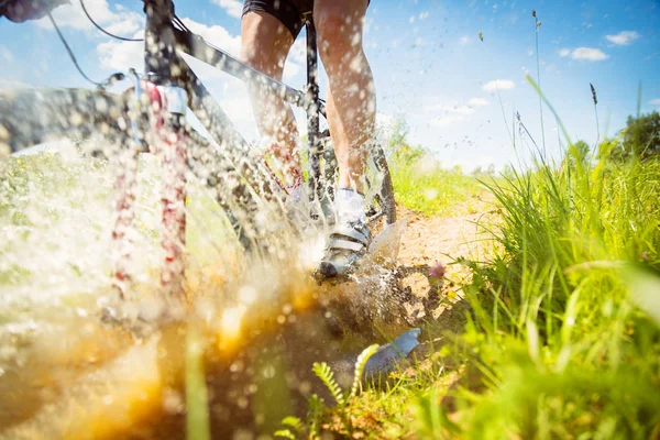 Mountain Biker cavalcando attraverso una pozzanghera sporca — Foto Stock