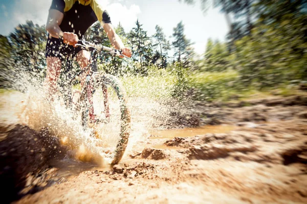 Mountain Biker cavalcando attraverso una pozzanghera sporca — Foto Stock