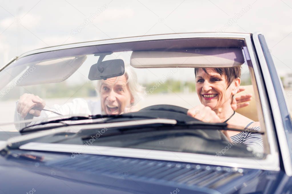 Senior Couple Driving A Convertible Classic Car