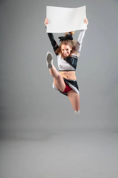Nuori cheerleader harmaalla taustalla — kuvapankkivalokuva