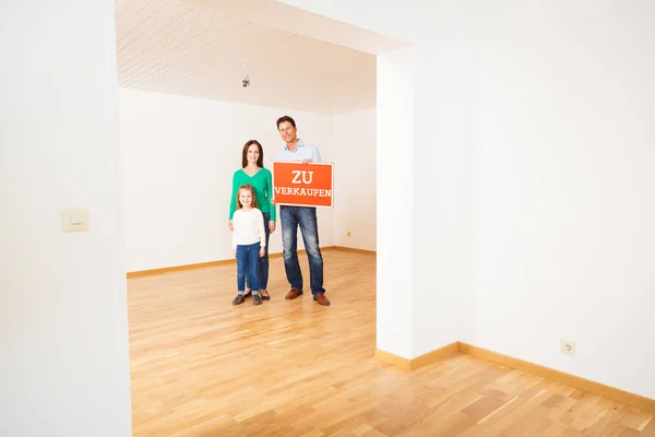 Família em apartamento vazio, segurando zu Verkaufen sinal — Fotografia de Stock