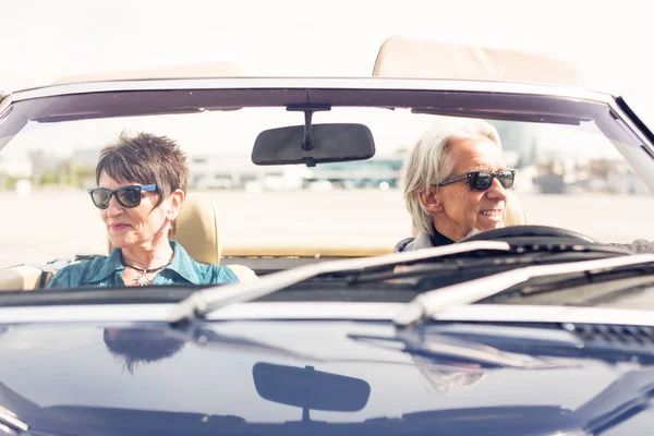 Casal sênior dirigindo um carro clássico conversível — Fotografia de Stock