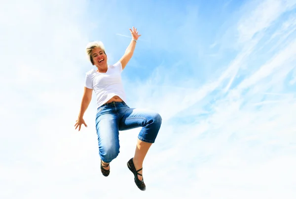 Žena v jejím 50s skákat vysoké do nebe — Stock fotografie