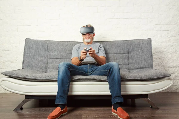 Senior Mann auf der Couch, spielt ein Vr-Spiel — Stockfoto