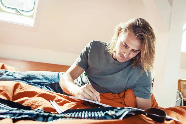 Junger Mann auf dem Bett, Zeichnung in Malbuch — Stockfoto