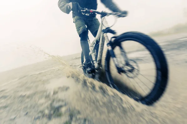 Mountain Biker corsa attraverso pozzanghera — Foto Stock