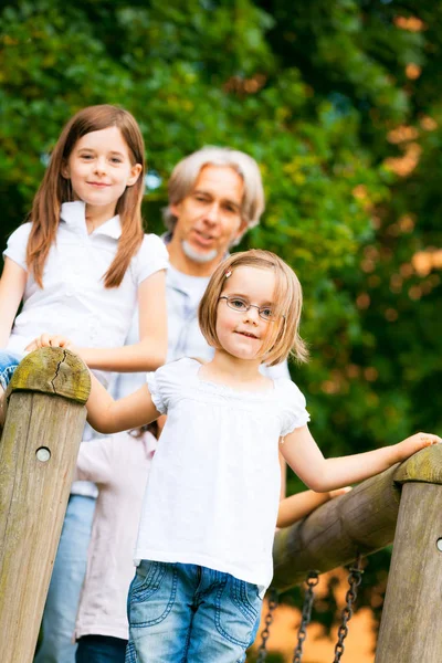 Trois enfants et leur grand-père jouant dehors — Photo