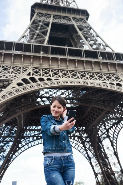 Young Chinese Female Tourist In Front Of The Eiffel Tower