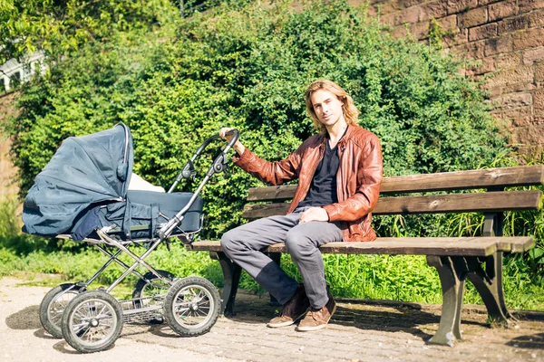 Pai jovem com carrinho de bebê no parque — Fotografia de Stock