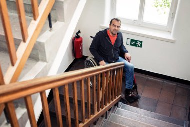 Adam merdivenlerde sıkışmış tekerlekli sandalyede