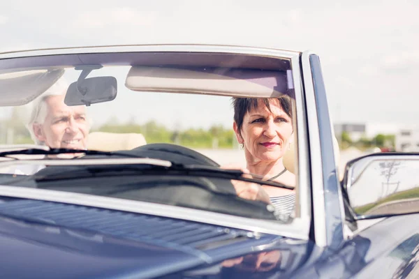 Casal sênior dirigindo um carro clássico conversível — Fotografia de Stock