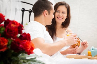 Çift yatakta kahvaltı yapıyor.