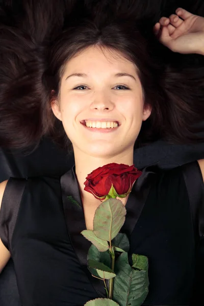 Νεαρή γυναίκα με ενιαίο τριαντάφυλλο, ξαπλωμένη — Φωτογραφία Αρχείου