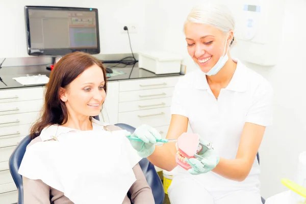 Asistente dental enseñando al paciente a cepillarse correctamente los dientes — Foto de Stock