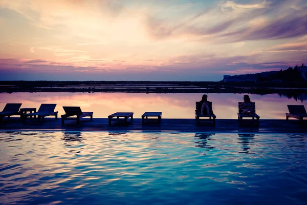 Mujeres disfrutando de la puesta de sol en la piscina —  Fotos de Stock