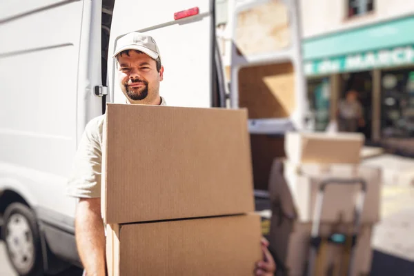 Mensajero entregando el paquete, de pie junto a su camioneta — Foto de Stock