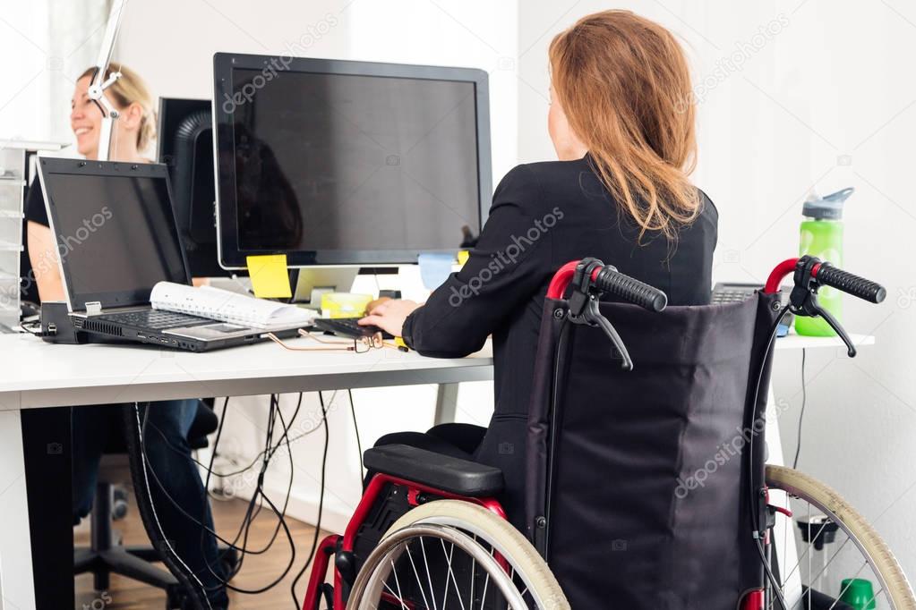 Woman Sitting In Wheelchair Working In Modern Office