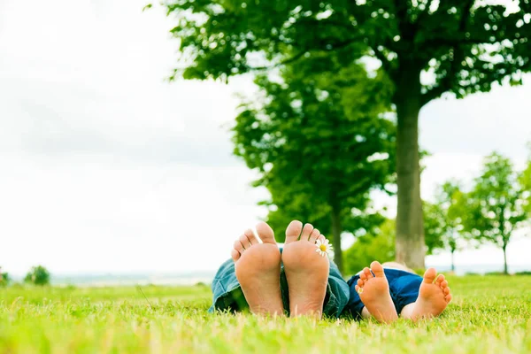 Kleine Mädchen und Väter Füße mit Gänseblümchen — Stockfoto