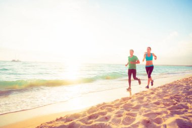 Genç bir çift sahilde koşuyor.